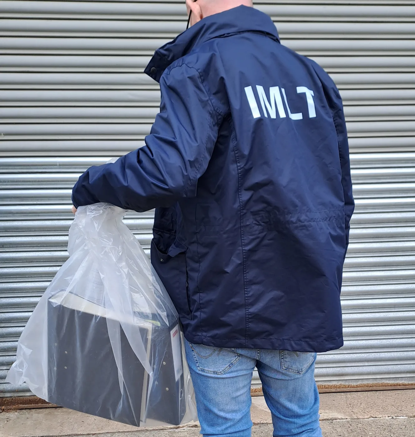 An England Illegal Money Lending Team officer carrying a bagged item (stock image)