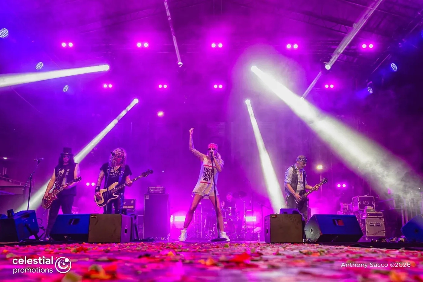The Guns N Roses Experience on an outdoor stage under purple lights, with petals scattered across the stage floor