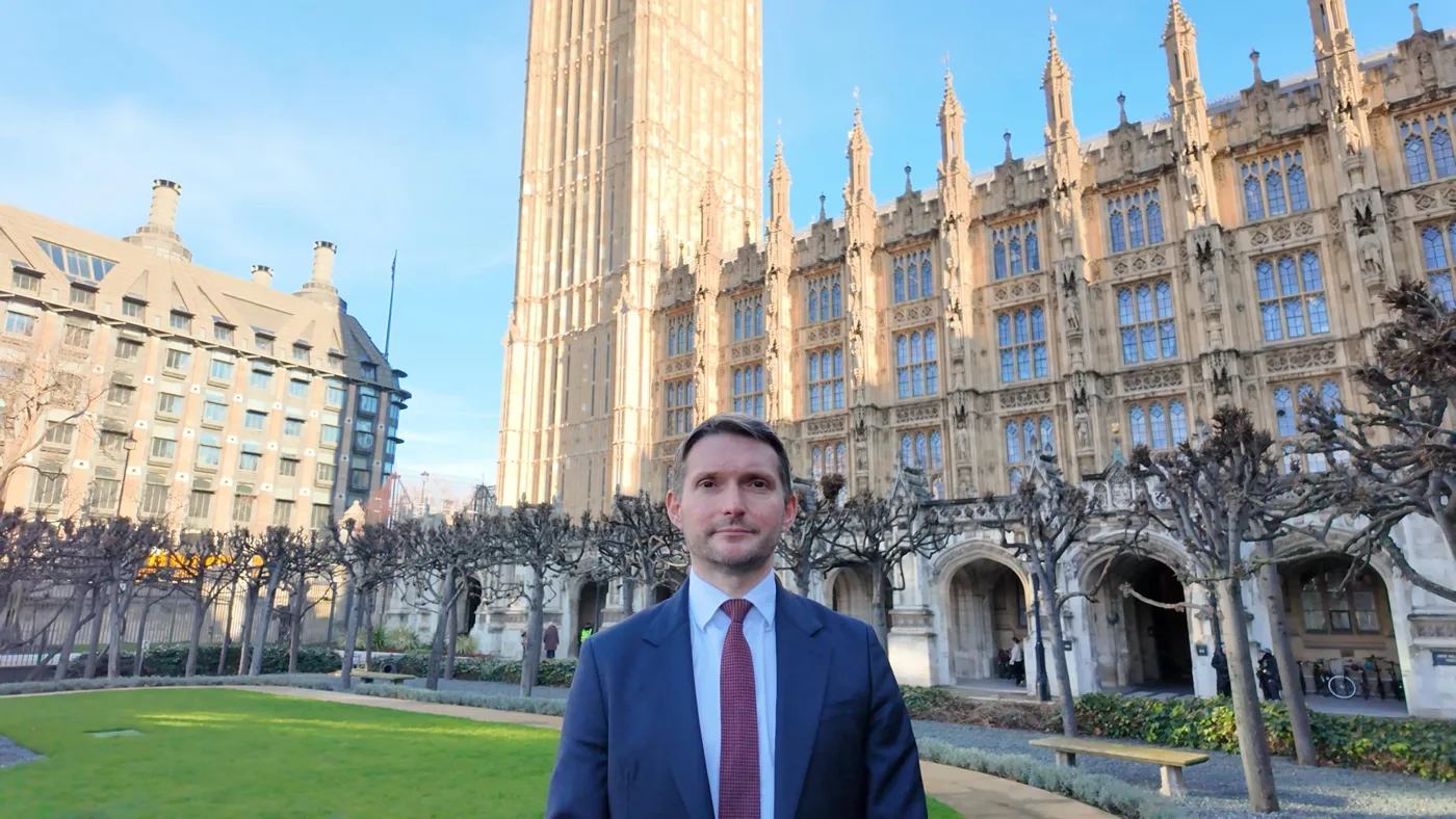 Chris Ward MP standing in front of the Palace of Westminster on a sunny day